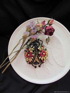 a white plate topped with flowers and an angel brooch sitting on top of it