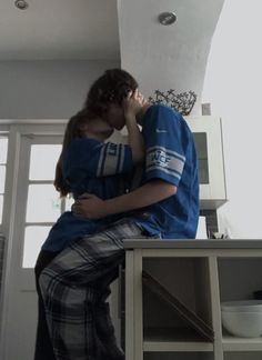 a young man and woman sitting on top of a table next to each other in front of a window