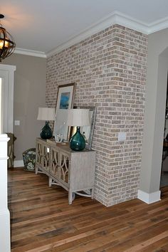 a living room filled with furniture and a brick wall next to a doorway that leads to a hallway