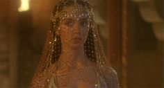 a woman in a white dress with gold sequins on her head and shoulders