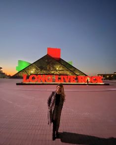 a woman standing in front of a building with a sign that says long live rock