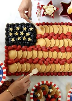 a flag shaped cake with strawberries and blueberries on the top is surrounded by other patriotic desserts