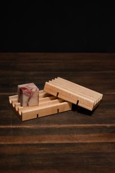 two pieces of soap sitting on top of a wooden tray next to another piece of wood