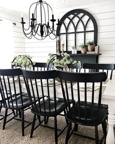 the dining room table is set with black chairs and white walls, while the chandelier hangs above it