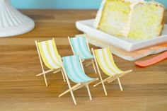 two miniature chairs and a piece of cake on a wooden table next to each other