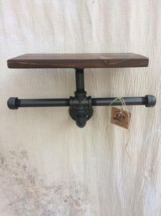 an iron pipe and wooden shelf with a tag hanging from it's side on a white wall