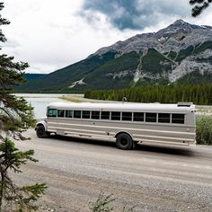 a white bus driving down a road next to a mountain