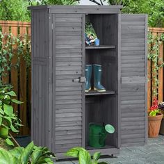 an outdoor storage shed with its doors open and gardening tools in the bottom shelf next to it