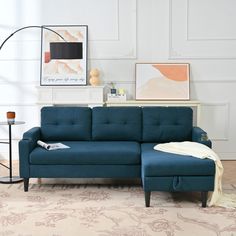 a blue couch sitting on top of a wooden floor next to a white table and lamp