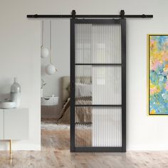 an open sliding glass door in a white room with wood flooring and artwork on the wall