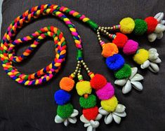 multicolored pom - pom necklaces with beads and flowers on a black background