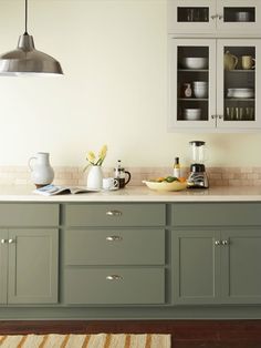 a kitchen with gray cabinets and white counter tops, an area rug on the floor