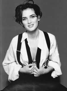 a black and white photo of a woman with her hands on her hips wearing suspenders