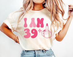 a woman wearing a t - shirt that says i am 39 + and has a peace sign on it