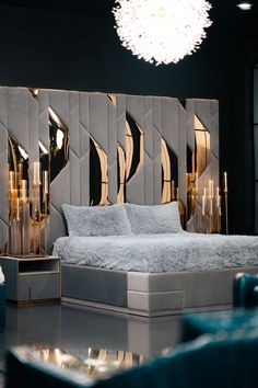 a modern bedroom with mirrored walls and gold accents on the headboard, along with an upholstered bed