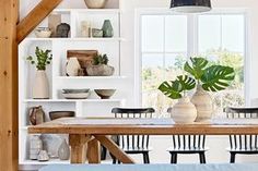 a dining room table with chairs and vases on it