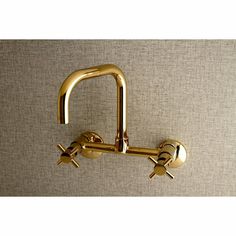 a gold faucet on the wall with two handles and three spouting holes