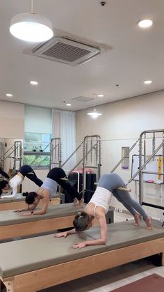 some people are doing yoga exercises in a room with metal railings and lights on the ceiling