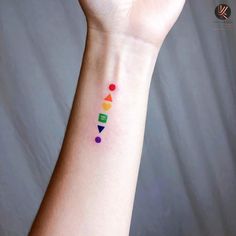 a woman's arm with a colorful tattoo on it that has geometric shapes and colors