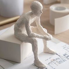 a white figurine sitting on top of a piece of paper