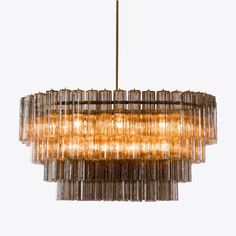 a chandelier made out of glass tubes hanging from a gold rod light fixture