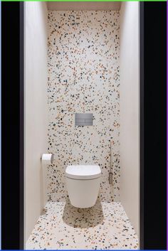 a white toilet sitting inside of a bathroom next to a wall mounted paper dispenser