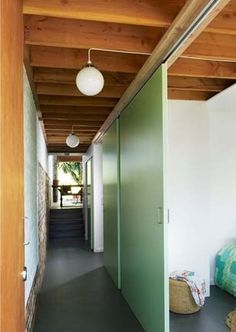 an empty hallway leading to a bedroom with green walls and wood ceilinging on the other side