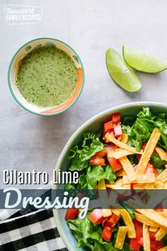 a bowl filled with salad and chips on top of a checkered table cloth next to a cup of green sauce