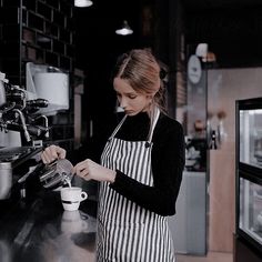 a woman in an apron is working at a coffee shop