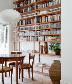 a dining room table and chairs with bookshelves in the background