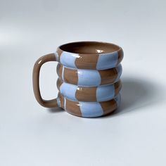 a brown and blue coffee cup sitting on top of a white table