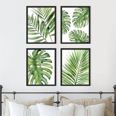 three green leaf prints hanging on the wall above a bed