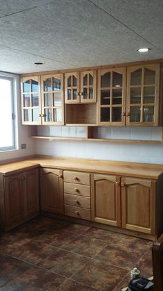 a kitchen with wooden cabinets and tile flooring in the middle of an empty room