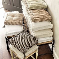 a stack of blankets sitting on top of a wooden floor next to a chair and ottoman