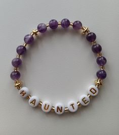 a beaded bracelet with the word haunted spelled in gold and white letters on it