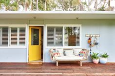 a white couch sitting on top of a wooden floor next to a yellow front door