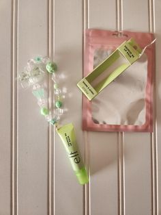 two green tubes sitting on top of a table next to a bag and beaded necklace