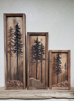 three wooden paintings with trees on them are sitting on a shelf next to each other