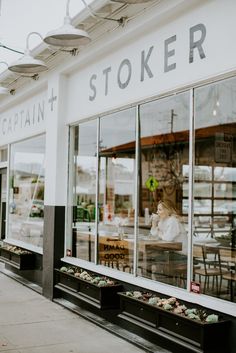 a store front with glass windows and plants in the window