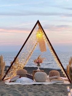 an outdoor seating area with pillows and lights on the beach