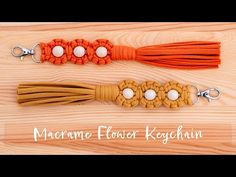 two orange and white tassels are on a wooden surface with the words marrame flower ketchup