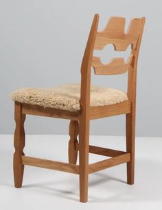 a wooden chair with a cushion on the seat and back rest, against a gray background