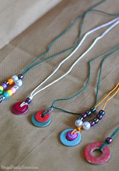 several necklaces are laid out on a brown paper bag with beads and buttons hanging from them