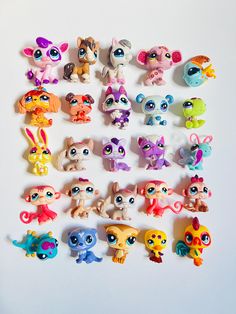 the littlest pet shop toys are lined up on the white surface, all in different shapes and sizes