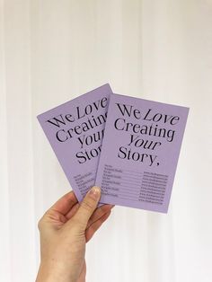 someone holding up two purple cards that say we love creating your story