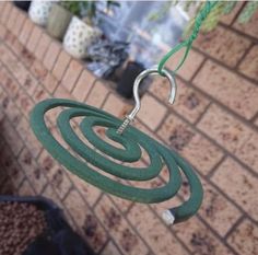 a green wind chime hanging from a brick wall