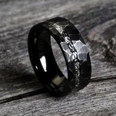 a black ceramic ring with silver inlays on top of a piece of wood