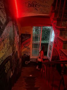 a woman is sitting on the stairs in an abandoned building with graffiti all over it