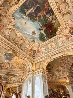 an ornate ceiling with paintings on it in a room that is painted gold and white