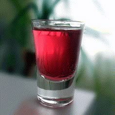 a glass filled with red liquid sitting on top of a table